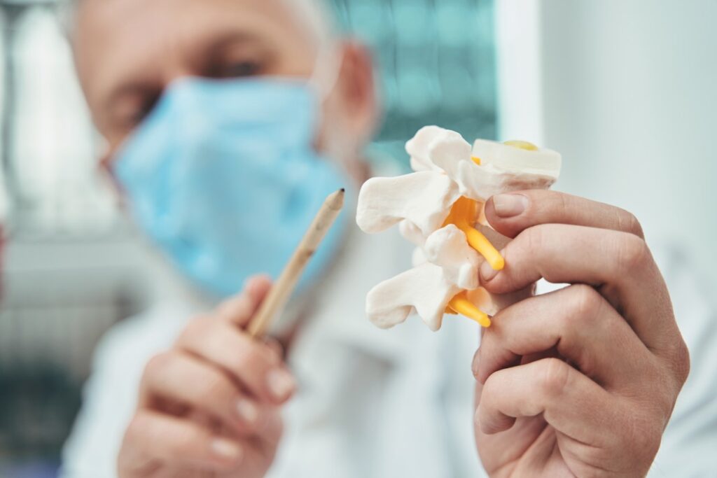 doctor in a face mask explaining the spine anatomy
