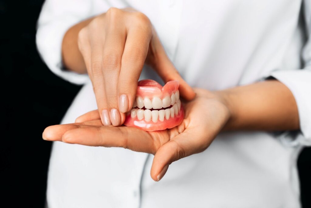 the dentist is holding dentures in his hands dental prosthesis in the hands of the doctor
